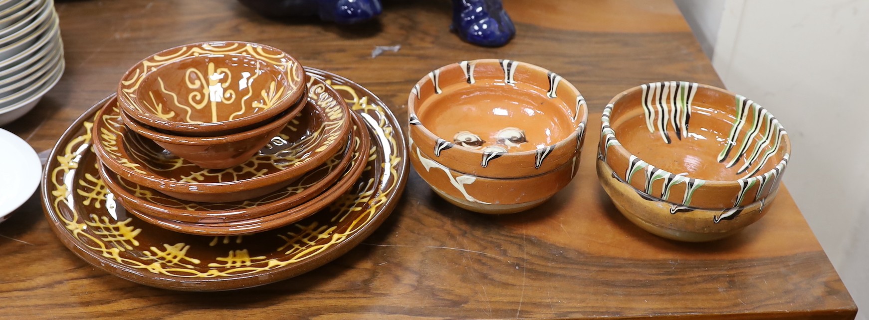 Four French pottery slip ware style pottery bowls and a pottery five similar dishes, largest 33cms diameter